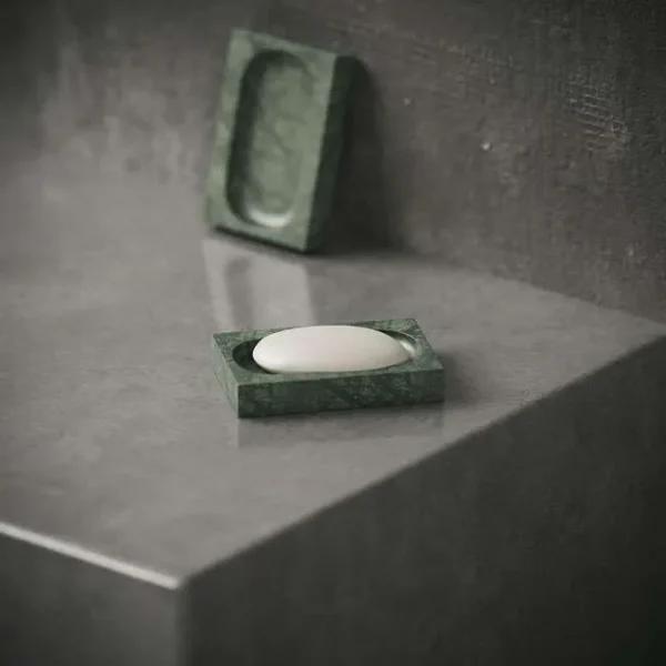 Elegant Verde Alpi marble soap dish displayed on a grey countertop – luxury green marble accessory for stylish interiors in Dubai and Abu Dhabi. صحن صابون من رخام فيردي آلبي الأخضر على سطح رمادي – إكسسوار رخامي فاخر للحمامات العصرية في دبي وأبوظبي