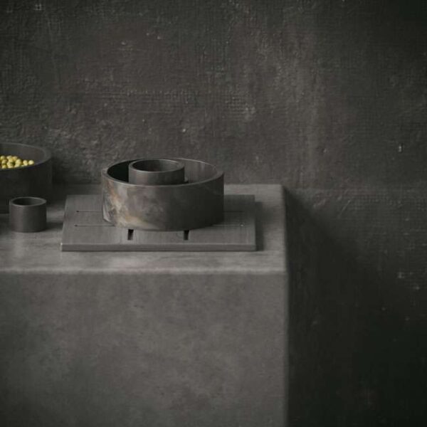 Modern marble accessory set arranged on a dark stone pedestal – luxury tabletop décor featuring bowls and containers in a stylish UAE interior. مجموعة إكسسوارات رخامية عصرية مرتبة على قاعدة حجرية داكنة – ديكور فاخر للطاولة يضم أوعية وحاويات في تصميم داخلي أنيق داخل الإمارات.