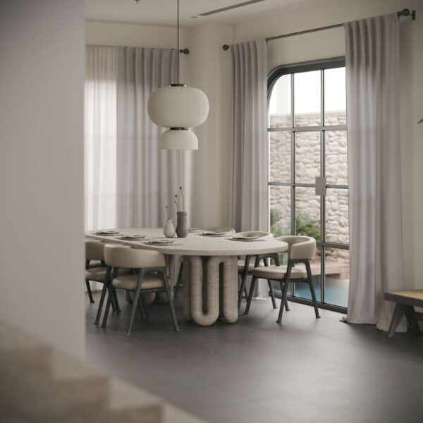 Elegant dining area featuring an oval travertine table and modern chairs, styled for luxury homes in the UAE. منطقة طعام أنيقة تحتوي على طاولة بيضاوية من الترافرتين وكراسي عصرية، مصممة للمنازل الفاخرة في الإمارات.