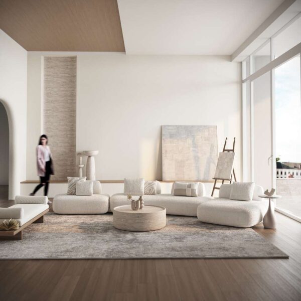 Sereno Sand Sofa in a sunlit contemporary living room, complemented by a round coffee table and neutral tones. كنبة سيرينو ساند في غرفة معيشة عصرية مضاءة بأشعة الشمس، تتكامل مع طاولة قهوة دائرية ودرجات ألوان حيادية.