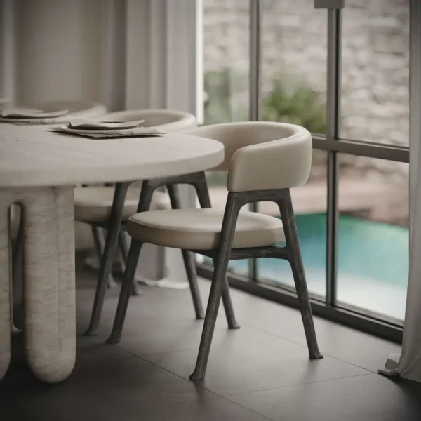 Modern dining chair with beige cushion next to an oval travertine stone dining table – luxury furniture in Dubai, UAE. كرسي طعام حديث مع وسادة بيج بجانب طاولة طعام بيضاوية من حجر الترافرتين - أثاث فاخر في دبي، الإمارات.
