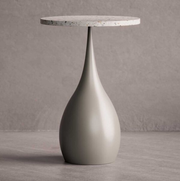 The Elara Slim Side Table features a slender, teardrop-shaped base in a smooth matte finish paired with a circular terrazzo top. Its elegant, elongated form brings a sense of sculptural lightness to any modern interior.