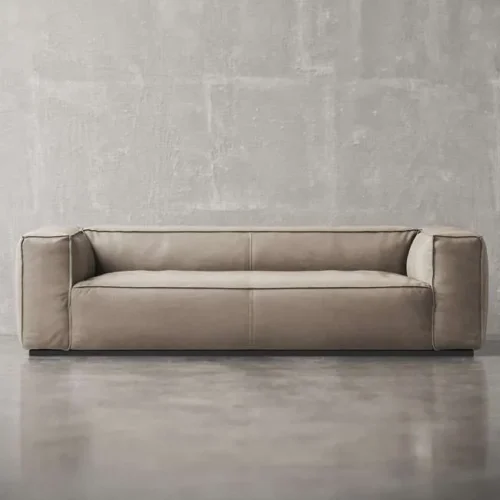 Modern beige suede sofa with wide arms and clean lines – luxury living room furniture in UAE كنبة فاخرة بلون بيج مع ذراعين عريضين وتصميم عصري – أثاث راقٍ لغرف المعيشة في الإمارات