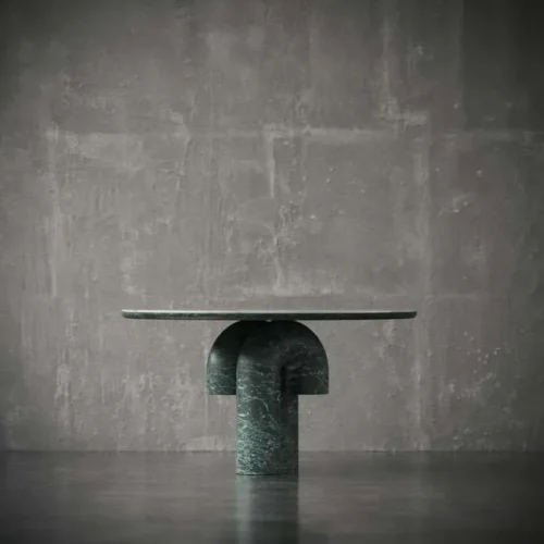 Side profile of the dining table showcasing the symmetry of the sculptural green marble base and thin marble top. صورة جانبية للطاولة تُظهر تناسق القاعدة الرخامية الخضراء النحتية وسطح الطاولة الرخامي الرقيق.
