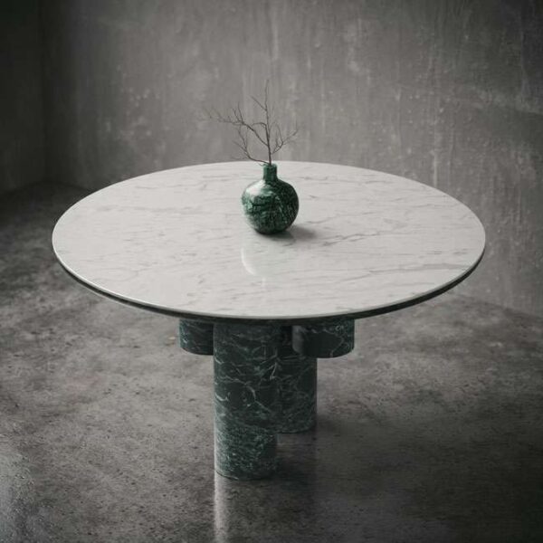 Round dining table styled with a green vase, highlighting the minimalist luxury and natural materials. طاولة طعام دائرية مزينة بإناء أخضر، تبرز الفخامة البسيطة والمواد الطبيعية في التصميم.