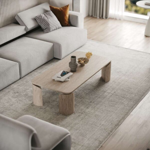 A softly lit modern living room featuring the Terrene Coffee Table in natural travertine stone. The table’s minimalist design with rounded edges and solid legs complements a neutral-toned sofa, layered textiles, and warm accent cushions for a serene aesthetic.