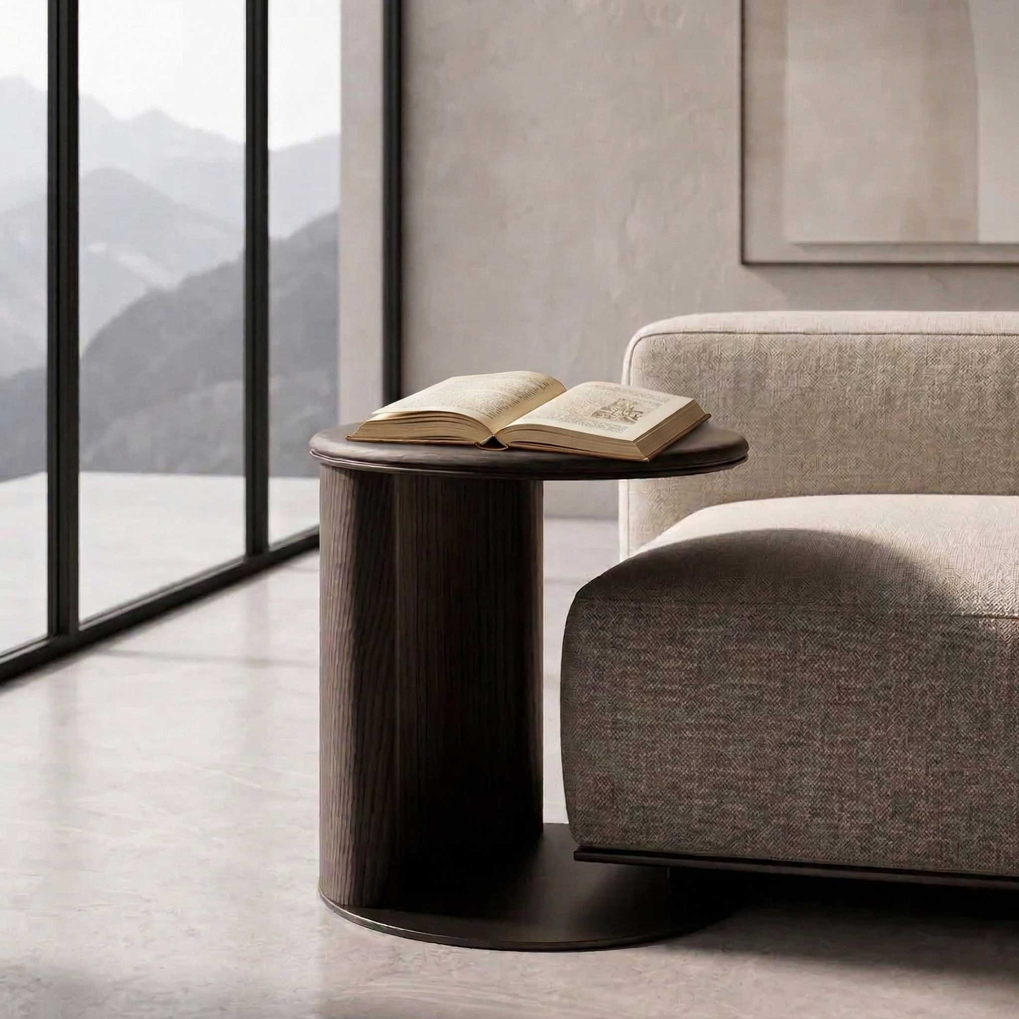 CaffeLinea Side Table featuring a minimalist cylindrical design with a curved wooden panel and circular tabletop. The smooth grain of the dark wood contrasts elegantly with the matte metal base, creating a refined, modern look.