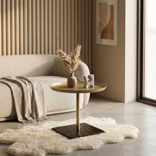 Luxury modern side table with a brushed metal tabletop and sculptural base, styled beside a plush contemporary sofa, showcasing refined designer furniture for elegant living room interiors in Dubai and Abu Dhabi, UAE.
