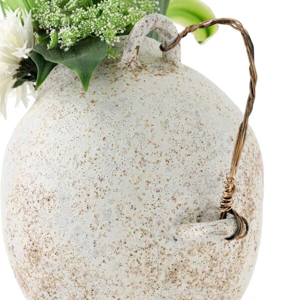 Close-up of rustic ceramic wire-handled vase with white artificial flowers – modern UAE home décor accessory. لقطة مقربة لمزهرية سيراميك ريفية بمقبض سلكي وزهور بيضاء صناعية – إكسسوار ديكور منزلي عصري في الإمارات