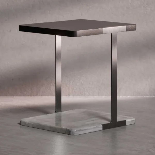 The Modan Side Table features a slim, brushed metal frame with a rectangular top and a solid marble base. The table’s minimal profile and clean lines evoke a refined modern aesthetic, highlighting the contrast between cool metal and natural stone