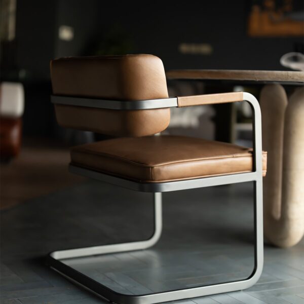 Side view of the Ironhide Dining Chair in a luxury interior setting, blending metal and leather craftsmanship for timeless elegance.