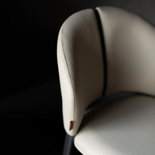 A luxurious off white dining chair in microfiber leather and steel , where comfort meets modern design. كرسي طعام من الجلد المايكروفايبر مع أرجل فولاذية مصقولة بلون أبيض أنيق.