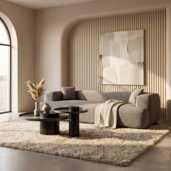 Luxury grey curved sofa with textured wall paneling and round black coffee tables in a sophisticated Dubai living room – premium furniture UAE.