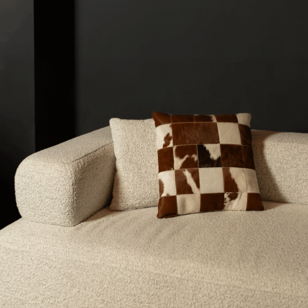 High-end cream boucle sofa with brown-and-white cowhide designer cushion, styled in a modern luxury interior in Dubai and Abu Dhabi, UAE.