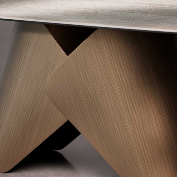Detail view of Knotta Dining Table sculptural metal base with brushed brass accents, highlighting its elegant curves and architectural design.